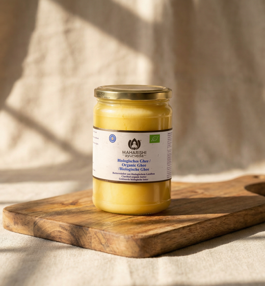 Bio-Ghee im Glas auf einem Holzbrett