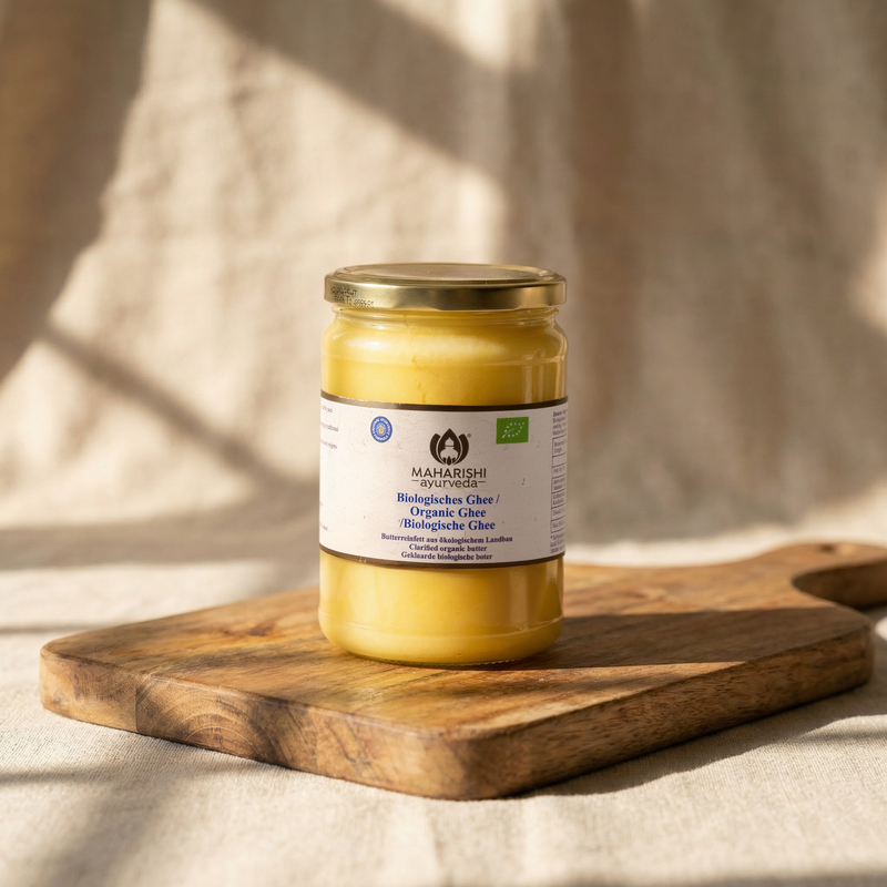 Bio-Ghee im Glas auf einem Holzbrett
